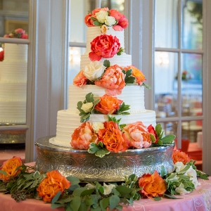 Gorgeous 4-tier wedding cake with coral and watermelon peonies and seeded eucalyptus