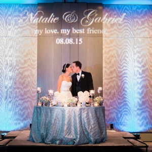 Bride and groom kissing at their sweetheart table with blue uplighting