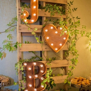 Marquee light monogram mounted on wooden pallet to create dessert bar sign