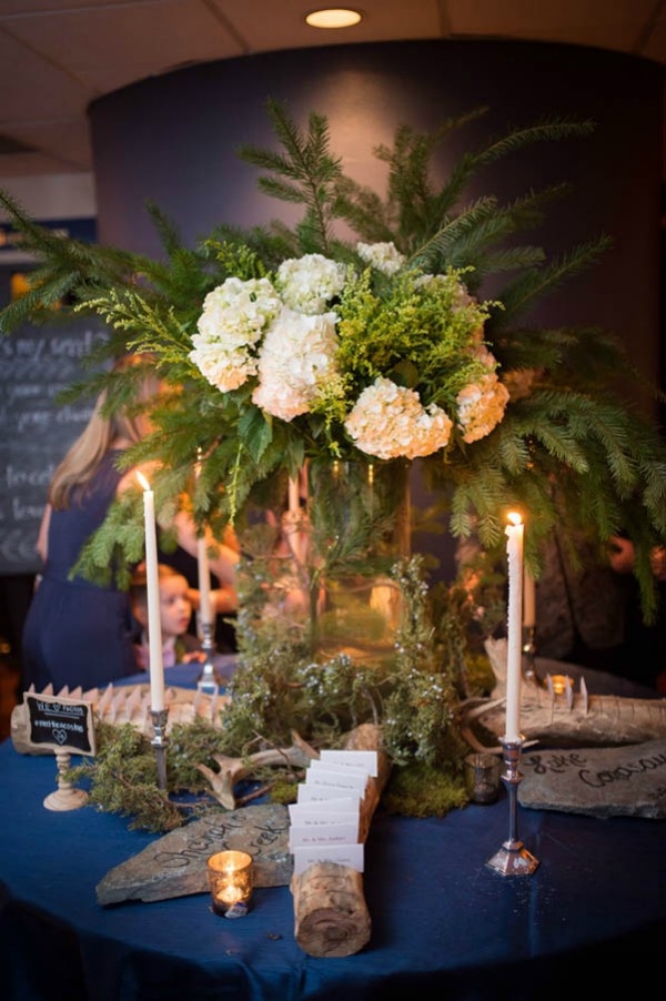 Enchanted forest escort card display with wooden logs, moss and pine branches