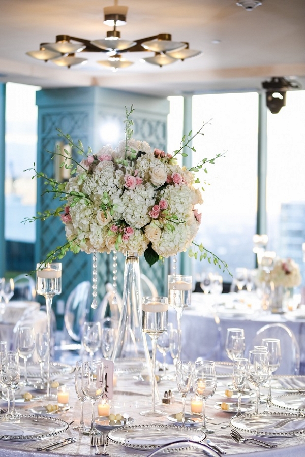 Glamorous wedding reception with tall centerpieces, clear chargers, crystal details and ghost chairs