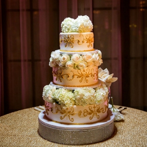 Versailles inspired wedding cake with gold piped details, rose and hydrangea layers, and a rhinestone cake stand