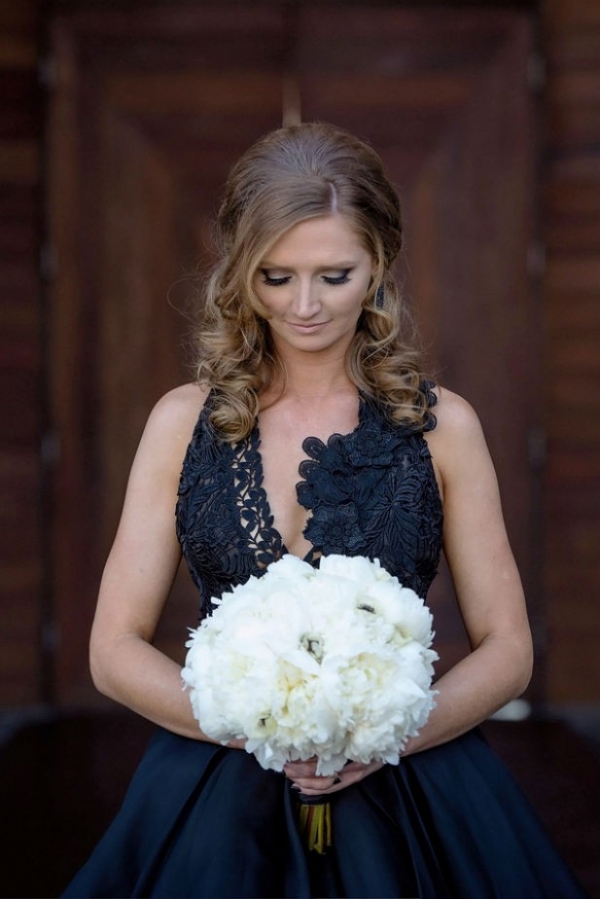 Modern bride wearing black wedding dress and holding bouquet of white peonies