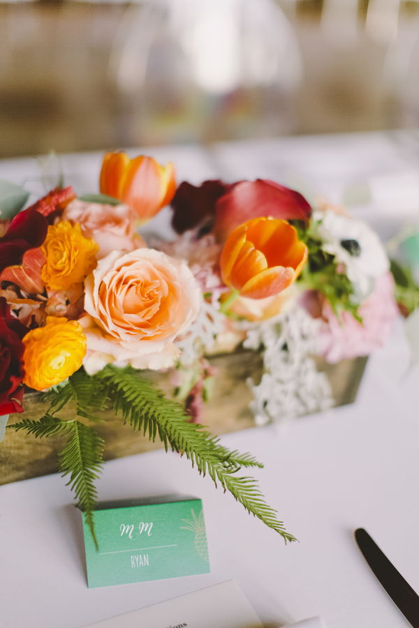 Colorful wedding centerpiece with tulips and roses in a wooden box and tropical green place card