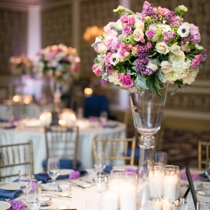 Elegant tall centerpiece with pink and purple flowers, a clear vase and candles