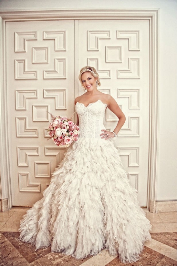 Luxe bride wearing corset wedding dress with feathered skirt, jeweled headband and updo