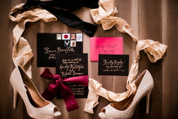 Romantic wedding invitation suite with black envelopes and gold calligraphy and ribbons