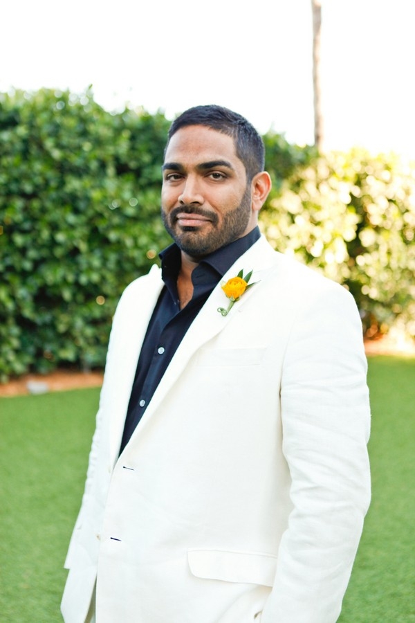 Chic South Beach groom wearing black shirt and white suit with neon orange boutonniere