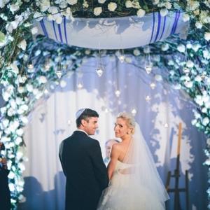 Whimsical floral chuppah with uplighting and hanging candles