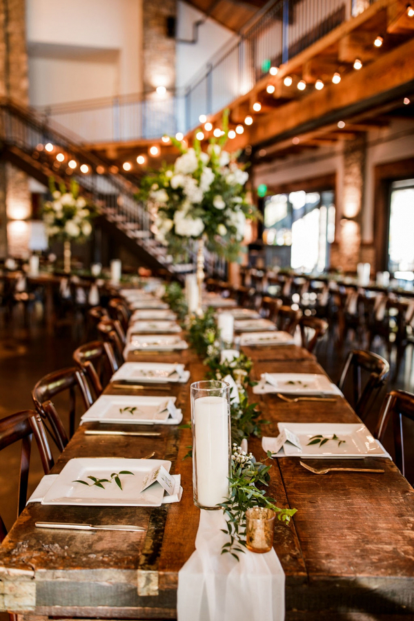 Long farm table wedding reception with greenery runner