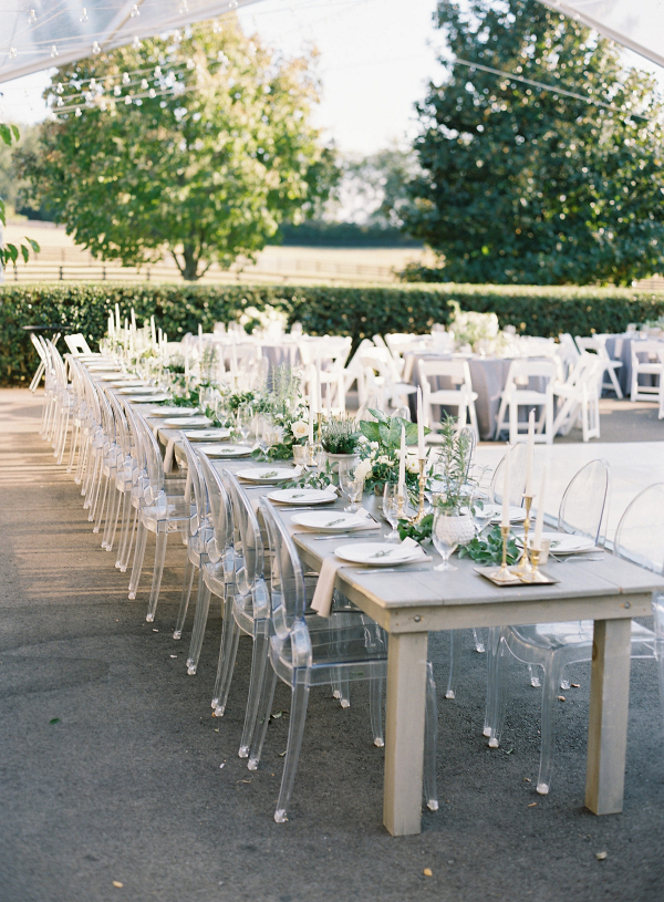 Outdoor wedding reception with farm tables and ghost chairs