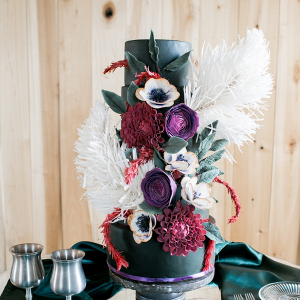 Black wedding cake with feathers and red and purple sugar flowers