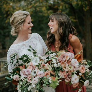 Bride in long sleeve lace gown with bridesmaid in rust dress