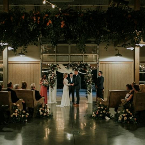 Barn wedding ceremony with hanging greenery and floral arch