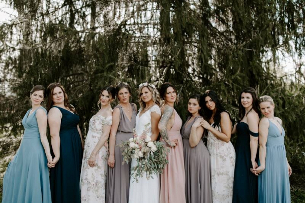 Bridesmaids in mismatched dresses of teal, blush, and beige