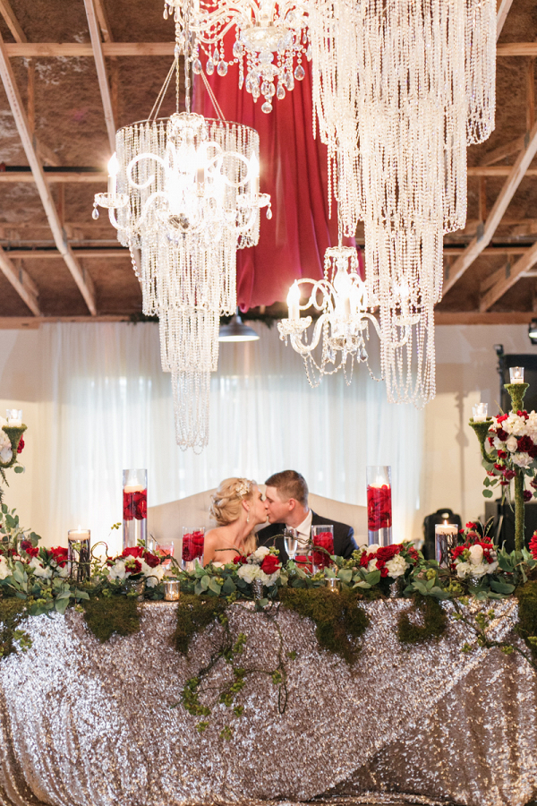 Couple sitting at sweetheart table with crystal chandeliers above