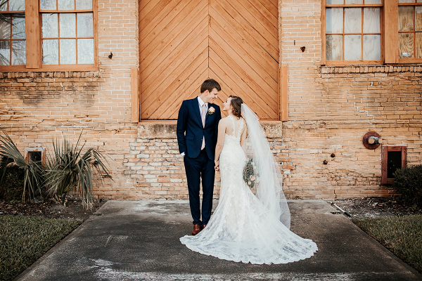 bride and groom standing in front of brick wall