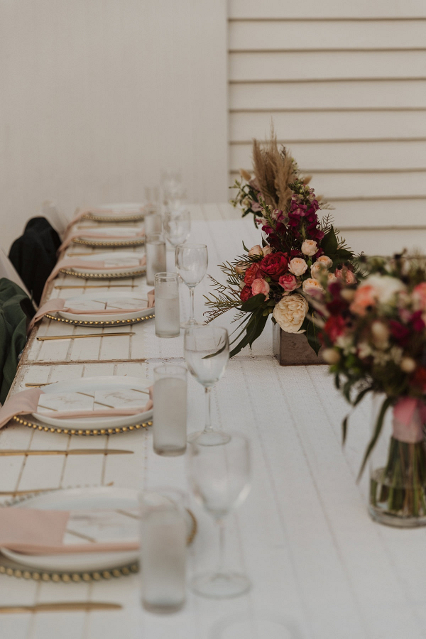 Wedding reception with long table and red florals