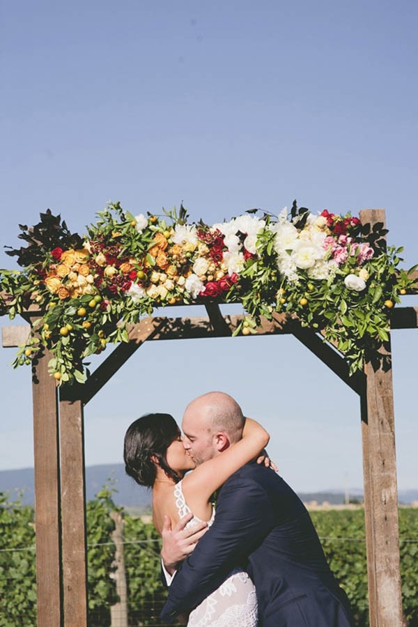 Newlyweds Kissing Under Floral Arch