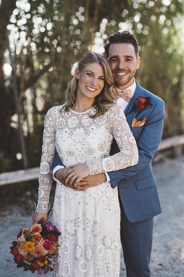 Bride in beaded long sleeve gown with groom in blue gray suit