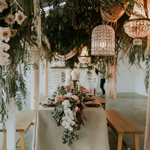 Boho wedding table with hanging greenery and chandeliers 