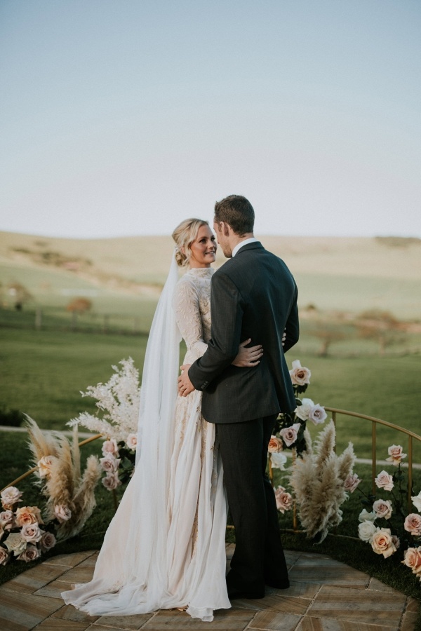 Outdoor wedding ceremony with semi circle floral backdrop