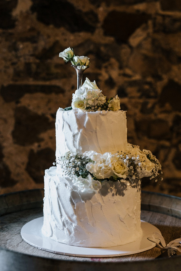 White buttercream wedding cake with fresh flowers