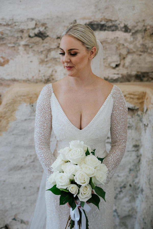 Bride in beaded wedding dress with classic white rose bouquet