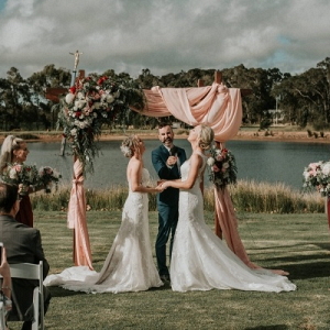 Outdoor wedding ceremony with draping and floral covered arch