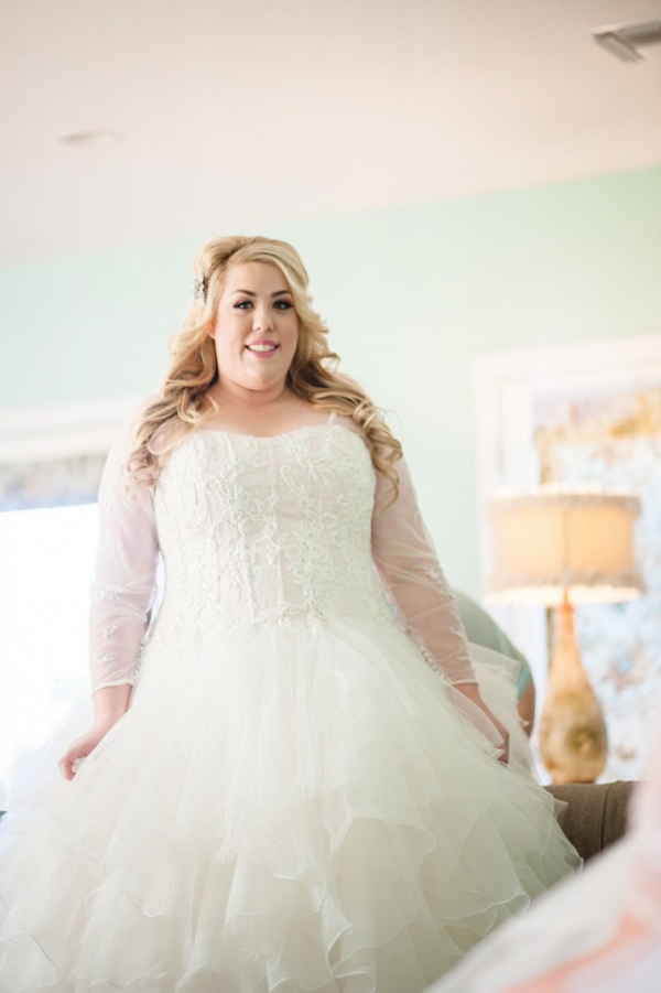 Plus Size Bride wearing a ruffled wedding dress with sheer sleeves 