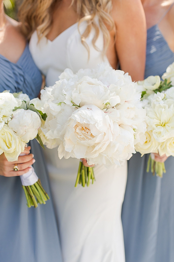 Bridal party in dusty blue gowns and white bouquets