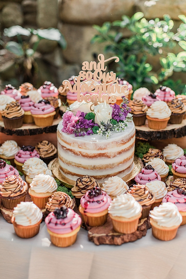 Semi naked wedding cake surrounded by cupcakes