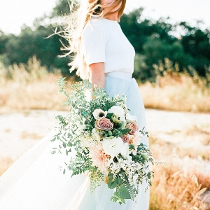Bride-to-be in blue tulle gown with large organic flowy bouquet.
