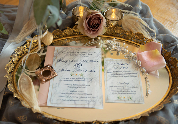 Wedding invitations on a gold tray with an amnesia rose