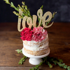 Glittery gold cake topper spelling out the word love