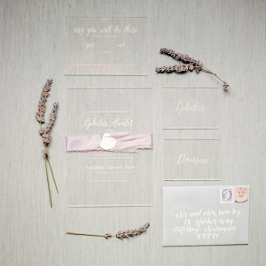 Calligraphed acrylic wedding invitation with a lavender belly band