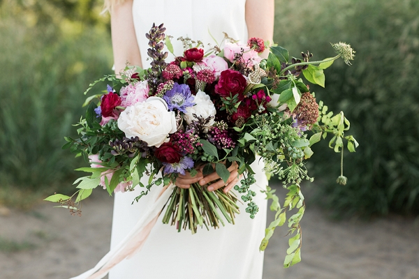 Jewel-toned bouquet with peonies, ranunculi, scabiosas, blueberries, Queen Anne's lace, and lupin