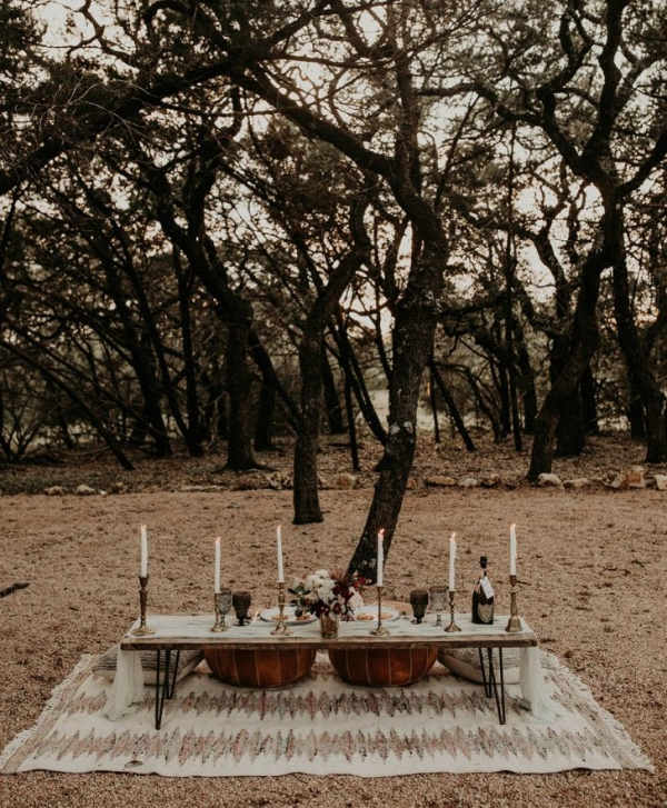 Boho wedding table in forest with pillows on rug