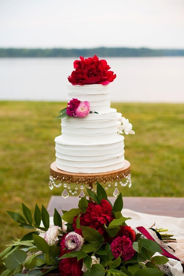 Tiered white wedding cake with peony cake topper